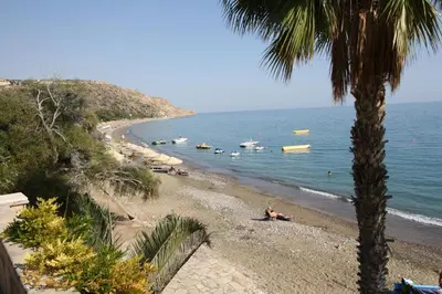 a beach with people and boats in the water at Maria Villa in Pissouri