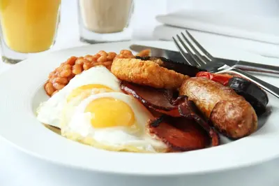a plate of breakfast food with eggs bacon sausage and beans at Alonia Villas in Pissouri