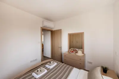 a small bedroom with a bed and a dresser at Pelagos apartment 6 in Paralimni