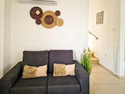 a living room with a black couch and some hats on the wall at Villa Green garden in Ayia Napa