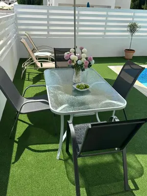 a table with chairs and a vase of flowers on a patio at LC Palm Villa in Protaras