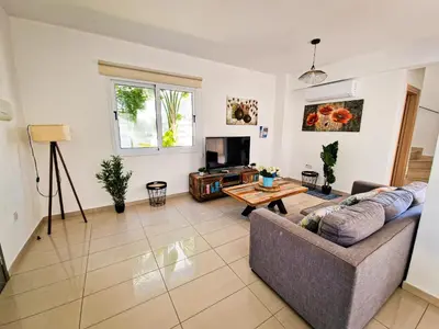 a living room with a couch and a tv at Nissi beach villa Oleandra in Ayia Napa