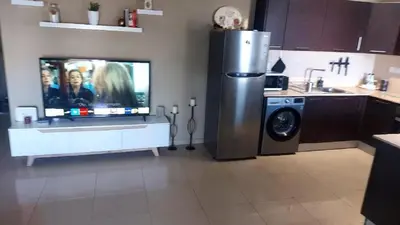 a kitchen with a tv and a washing machine at Paramount Gardens Resorts C202 in Larnaka