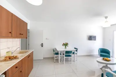 a kitchen with a table and blue chairs at Mia Hotel Apartment in Ayia Napa