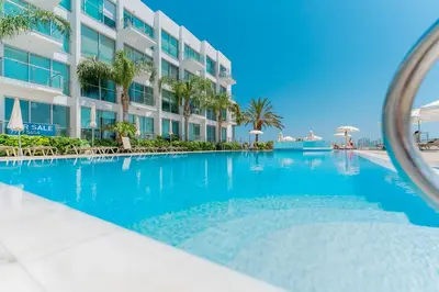 a swimming pool in front of a building at VERONICA - Coralli Beachfront Apartment in Protaras