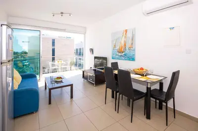 a living room with a table and a blue couch at SHARON - Coralli Beachfront Apartment in Protaras