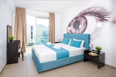 a bedroom with a blue and white bed and a window at SHARON - Coralli Beachfront Apartment in Protaras