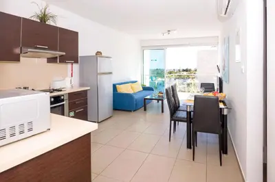 a kitchen and living room with a table and chairs at SHARON - Coralli Beachfront Apartment in Protaras
