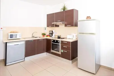 a kitchen with brown cabinets and a white refrigerator at SHARON - Coralli Beachfront Apartment in Protaras