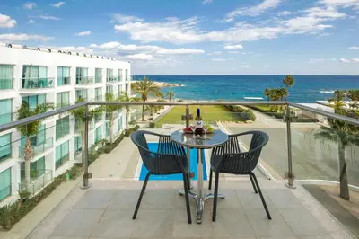 a balcony with a table and chairs and the ocean at GABRIELA - Coralli Beachfront Apartment in Protaras