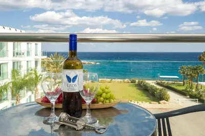 a table with a bottle of wine and two wine glasses at GABRIELA - Coralli Beachfront Apartment in Protaras