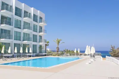 a hotel with a swimming pool next to a building at GABRIELA - Coralli Beachfront Apartment in Protaras
