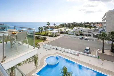 a balcony with a pool and a tennis court at LAILA - Coralli Beachfront Apartment in Protaras