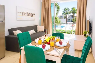 a living room with a table and chairs and a couch at ALICIA - Coralli Beachfront Apartment in Paralimni