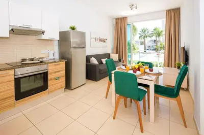 a kitchen and living room with a table and chairs at ALICIA - Coralli Beachfront Apartment in Paralimni