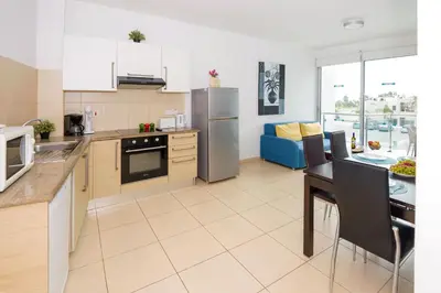 a kitchen with a table and a refrigerator and a dining room at BLISS - Coralli Beachfront Apartment in Protaras