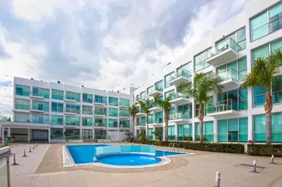 an apartment building with a swimming pool in front of it at BLISS - Coralli Beachfront Apartment in Protaras