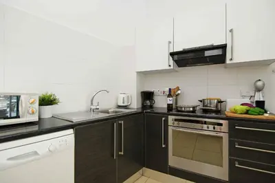 a kitchen with black cabinets and white appliances at DIANA - Coralli Beachfront Apartment in Protaras