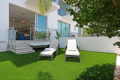 a table and chairs on a lawn in front of a house at MERYL - Coralli Beachfront Apartment in Protaras