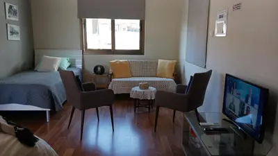 a living room with a bed and chairs and a television at Extremely comfy apt with spacious private terrace 10min walk to the beach & in Town in Larnaka