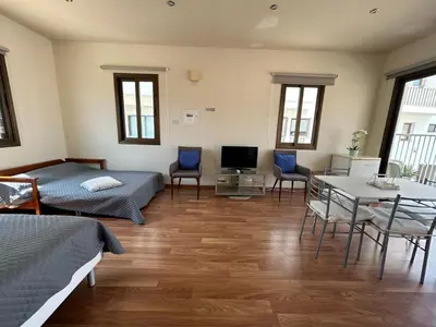 a room with two beds and a table and chairs at Extremely comfy apt with spacious private terrace 10min walk to the beach & in Town in Larnaka
