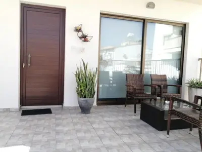 a porch with a wooden door and chairs at Extremely comfy apt with spacious private terrace 10min walk to the beach & in Town in Larnaka