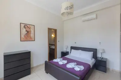 a bedroom with a large bed with a purple blanket at Sparta Luxury Villa in Protaras