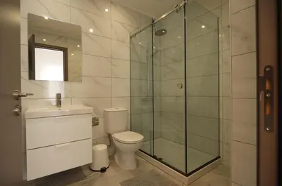 a bathroom with a toilet and a glass shower at Maison Zenon Larnaca City Center apartments in Larnaka