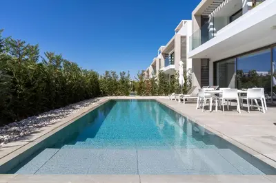 a swimming pool with tables and chairs next to a house at Waves 3-Bedroom Villa in Protaras in Paralimni