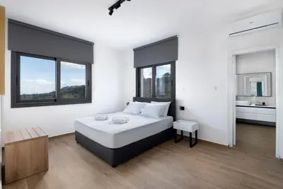 a white bedroom with a bed and a bathroom at The Oasis in Protaras