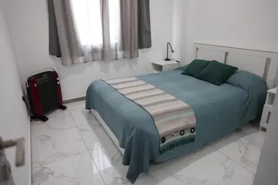 a bedroom with a bed and a suitcase in it at Όμορφο καινούργιο διαμέρισμα σε μικρή πολυκατοικία in Voroklini