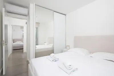 a white bedroom with a white bed and a mirror at The MedView Garden House in Pervolia