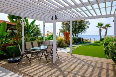 a white pergola on a patio with a table and chairs at The MedView Garden House in Pervolia