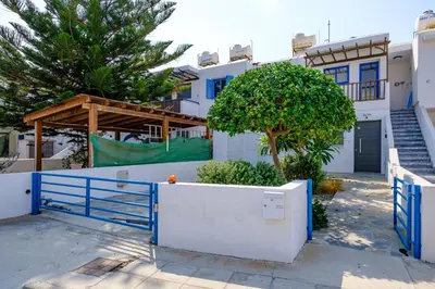 a house with a blue gate and a tree at The MedView Garden House in Pervolia