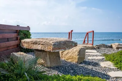 a stone bench sitting next to the ocean at The MedView Garden House in Pervolia