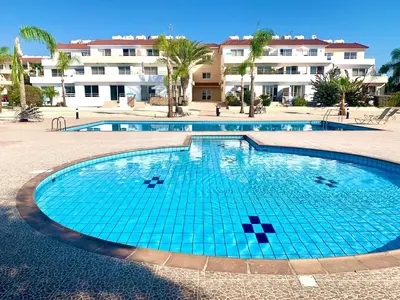 a swimming pool with blue water in front of a building at Nissi 3 C14 Sea View Top Floor Apartment in Ayia Napa