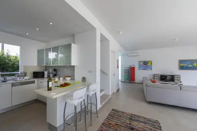 a white kitchen and living room with a couch at Oceania Villa in Protaras