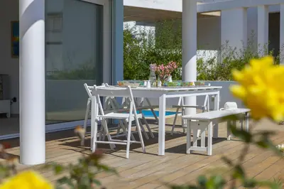 a white table and chairs on a deck with flowers at Oceania Villa in Protaras