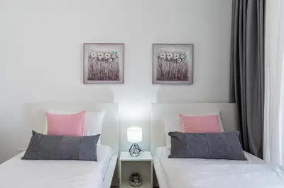 a bedroom with two beds with pink and grey pillows at Aziza 1- Bedroom Apartment in Larnaca in Larnaka