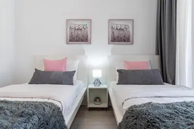 two twin beds in a room with white and pink at Aziza 1- Bedroom Apartment in Larnaca in Larnaka