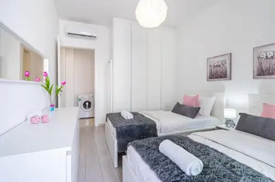 a white room with two beds and a couch at Aziza 1- Bedroom Apartment in Larnaca in Larnaka