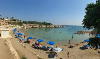 a group of people on a beach with blue umbrellas at Carme at the Beach - Mythical Sands in Paralimni