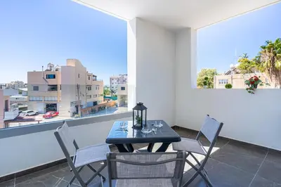 a table and chairs on a balcony with a view of a city at Kmeidos 1-Bedroom Apartment in Larnaca in Larnaka