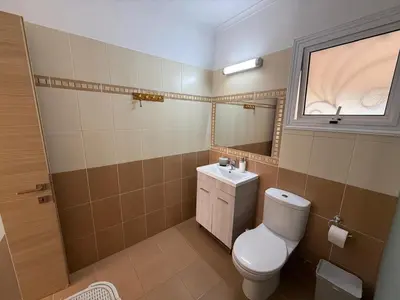 a bathroom with a toilet and a sink and a window at Nissi Golden Sands Sunny Apartment A1D4 in Ayia Napa