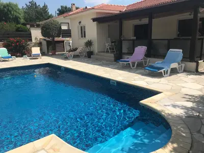 a swimming pool with chairs and a house at LE CAROUBIER splendid 3 bedrooms bungalow in Zanaja