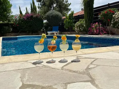 four wine glasses with flowers in them next to a swimming pool at LE CAROUBIER splendid 3 bedrooms bungalow in Zanaja