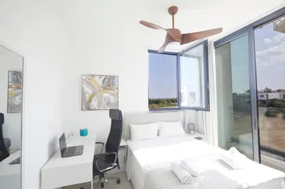 a bedroom with a bed and a desk and a window at Almaria Villas in Protaras