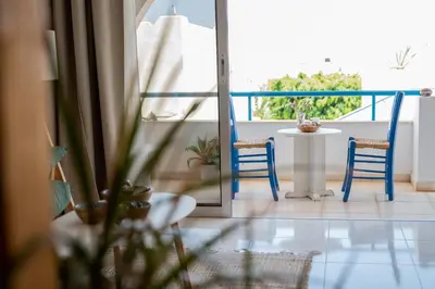 a balcony with a table and two blue chairs at Pissouri bay studio in Pissouri