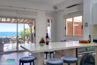 a kitchen with a counter with stools and a view of the ocean at Beachfront Villa Carpe Diem in Mor Menekshe