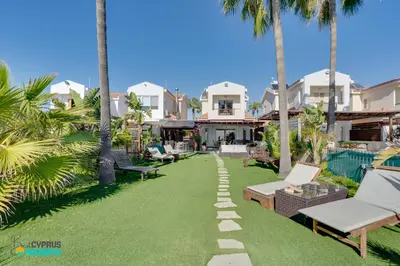 a backyard with palm trees and a lawn with a pathway at Beachfront Villa Carpe Diem in Mor Menekshe